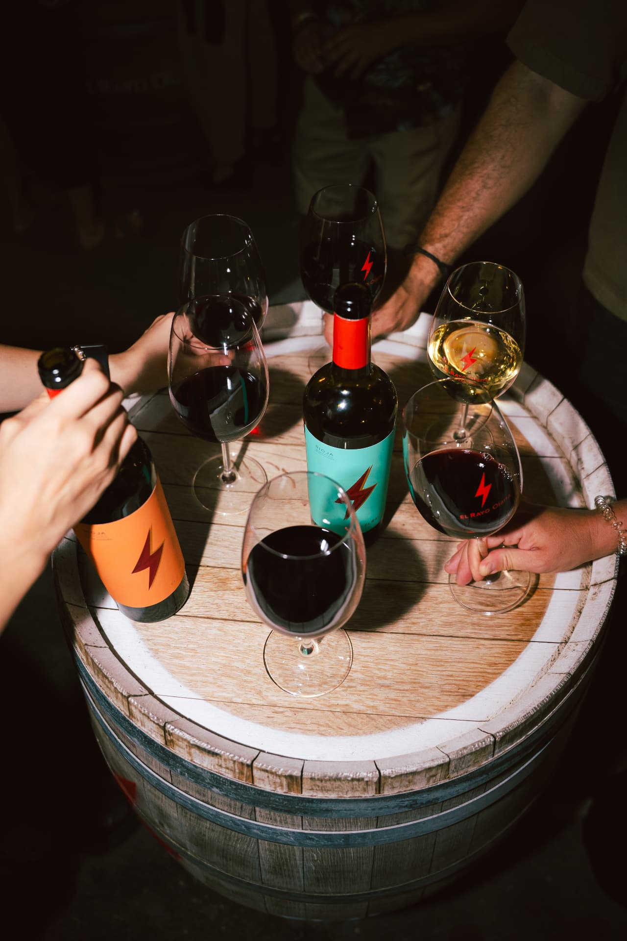 Copas y botellas de El Rayo sobre un barril de vino