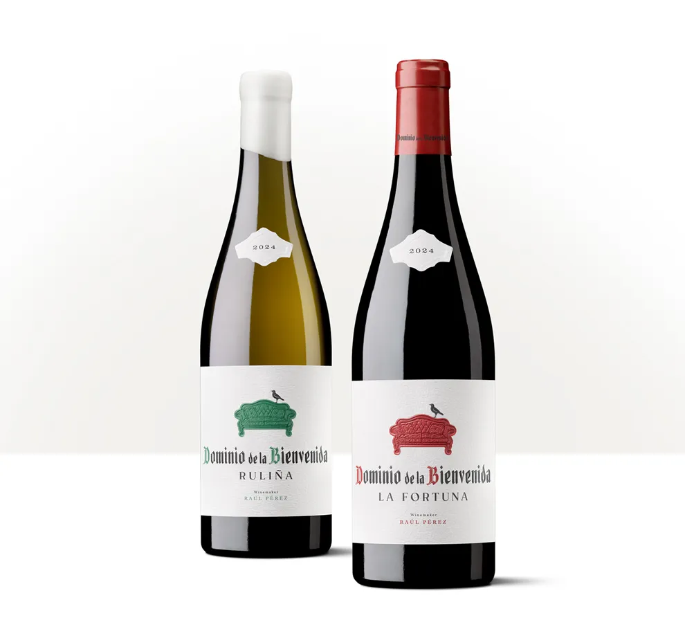 Siluetas de dos botellas de Dominio de la Bienvenida La Fortuna con etiquetas de distintos acentos cromáticos y un sofá rojo en relieve.