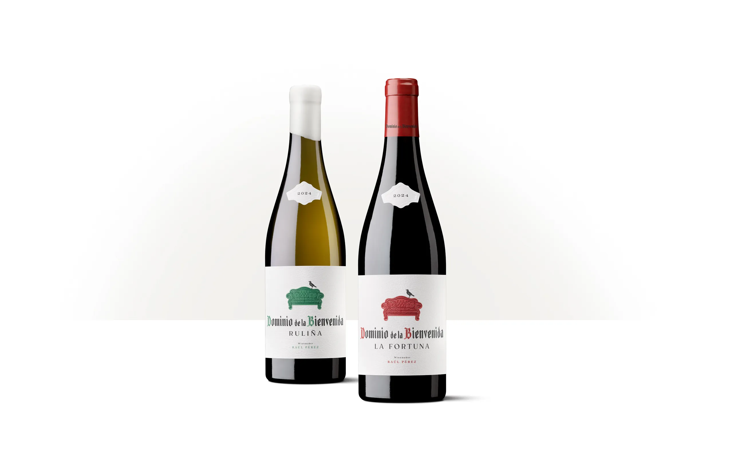 Siluetas de dos botellas de Dominio de la Bienvenida La Fortuna con etiquetas de distintos acentos cromáticos y un sofá rojo en relieve.