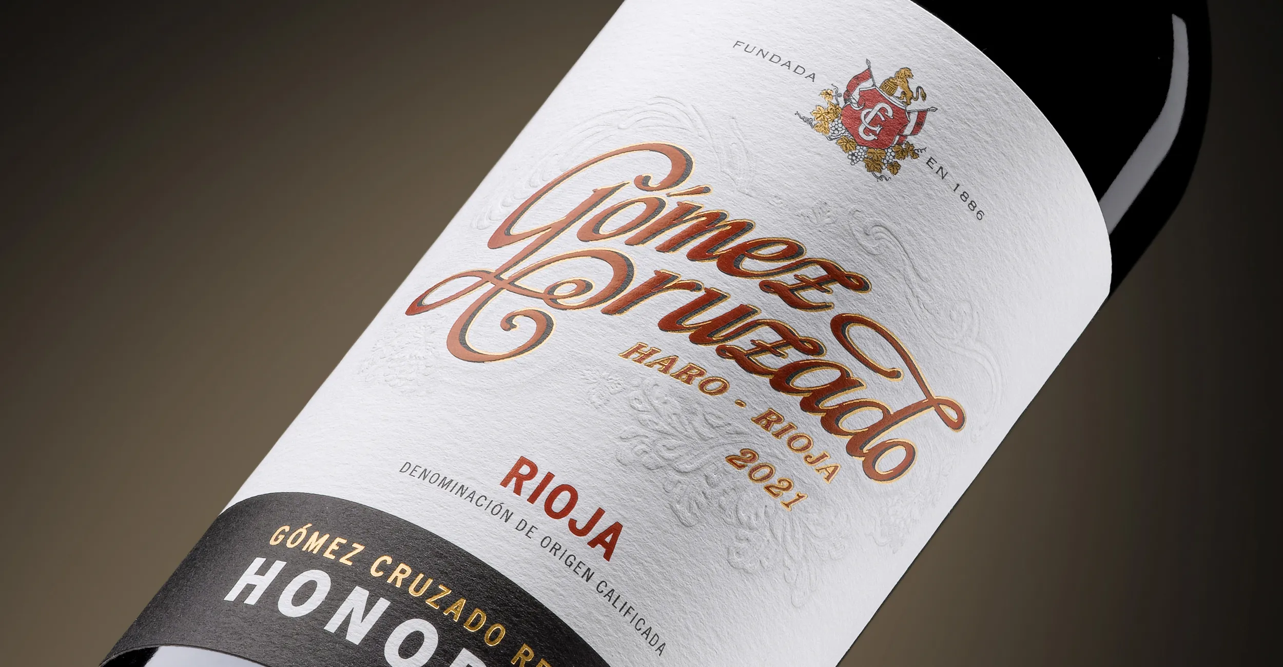 Botella de Honorable de Bodegas Gómez Cruzado, con etiqueta blanca y detalles en rojo y dorado.