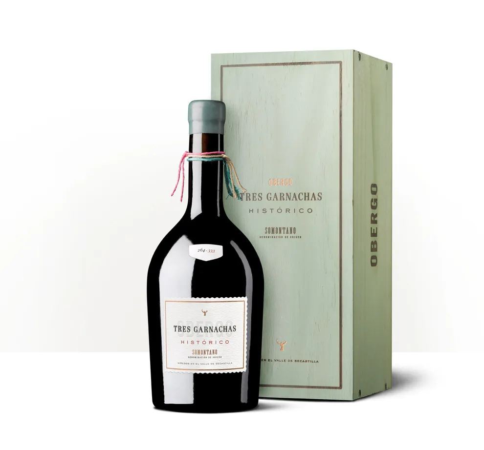 Silueta de una botella de Obergo Histórico Tres Garnachas junto a su estuche verde claro.