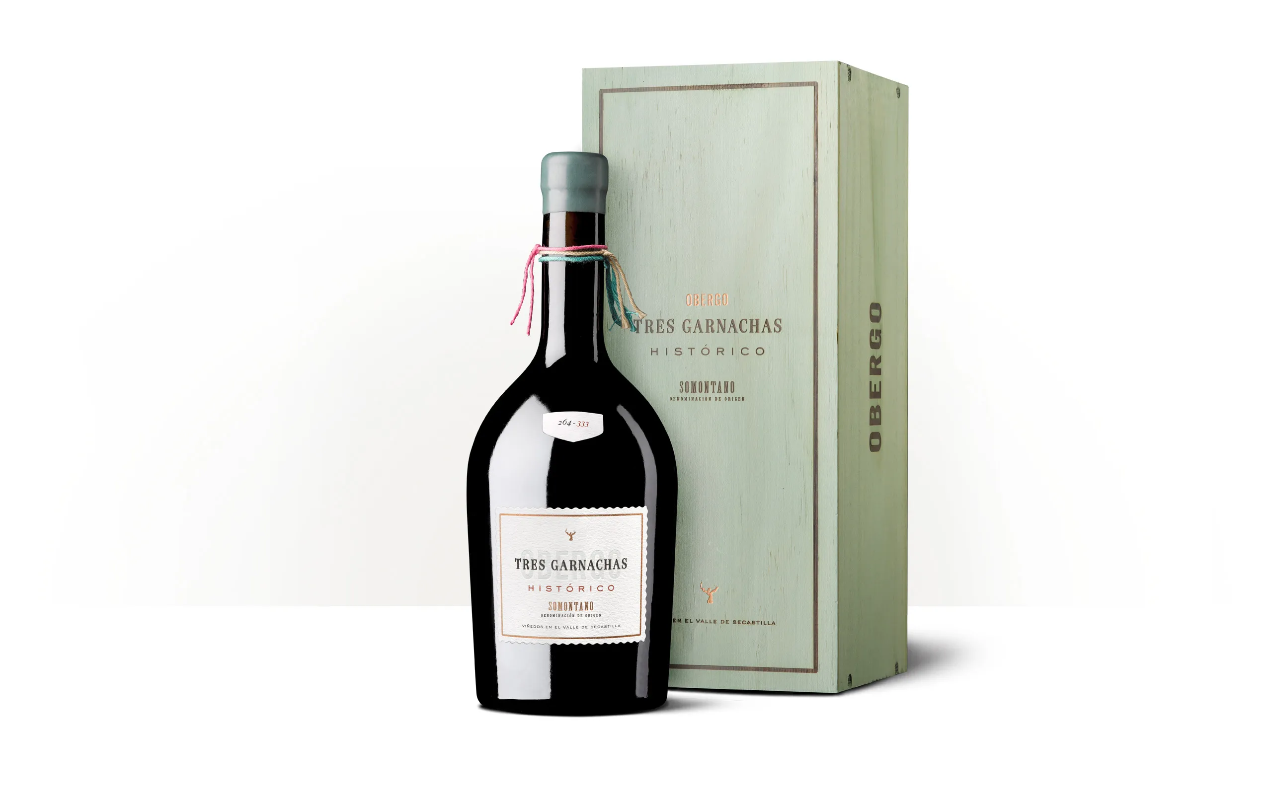 Silueta de una botella de Obergo Histórico Tres Garnachas junto a su estuche verde claro.