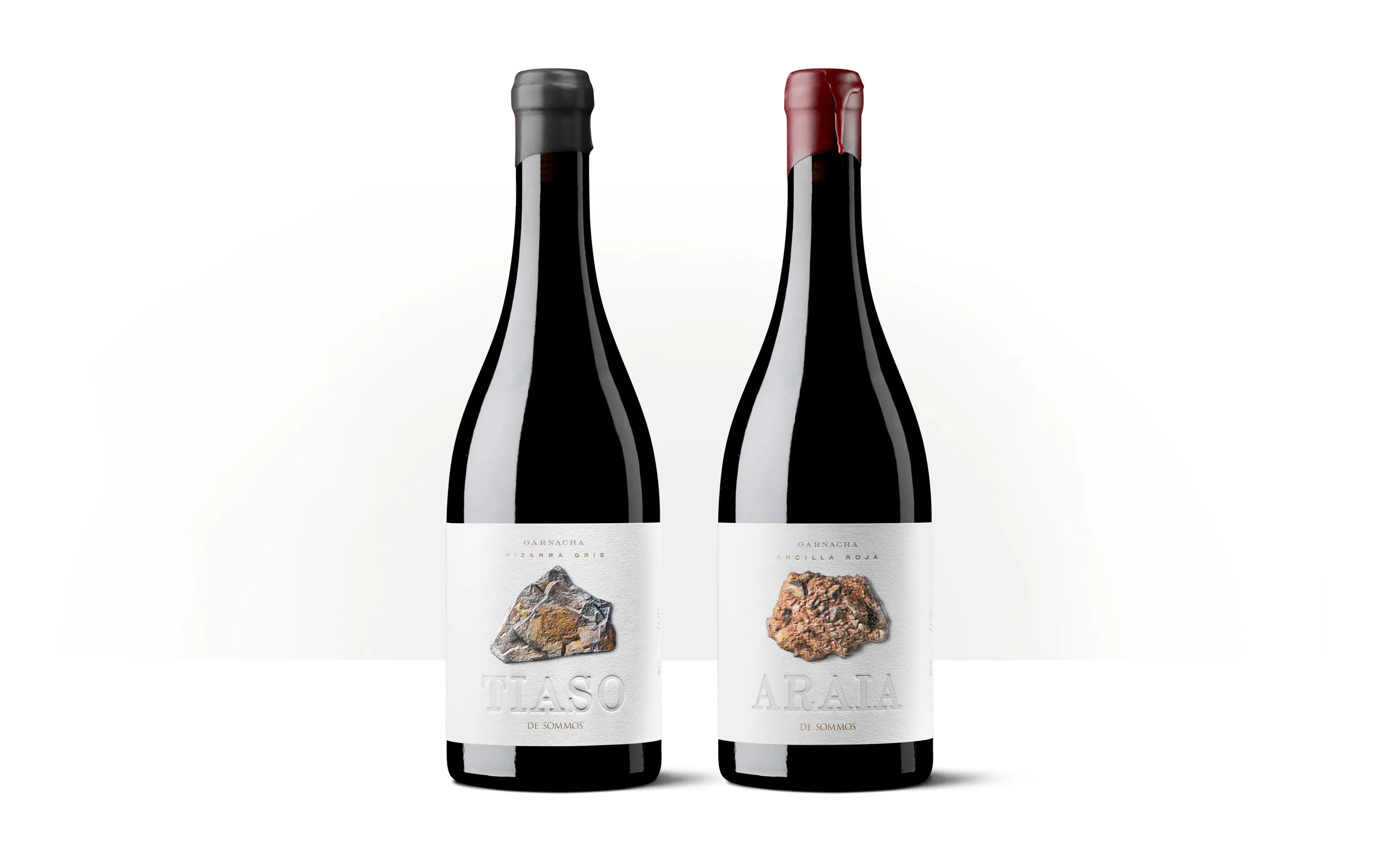 Siluetas de dos botellas de vino Tiaso y Araia de Bodegas Sommos, con etiquetas ilustradas.